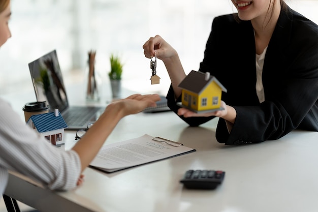 Agente imobiliário segurando a chave da casa para seu cliente após a assinatura do contrato no escritórioconceito para mudança de casa ou aluguel de imóveis