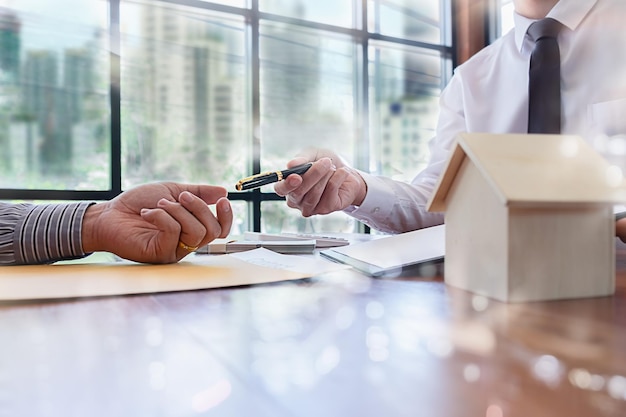 Foto agente inmobiliario dando una pluma a un cliente en la mesa de la oficina