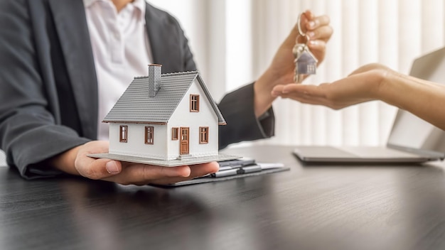 Agente inmobiliario con una llave y pidiendo al cliente un contrato para comprar, obtener un seguro o un préstamo de bienes raíces o propiedades