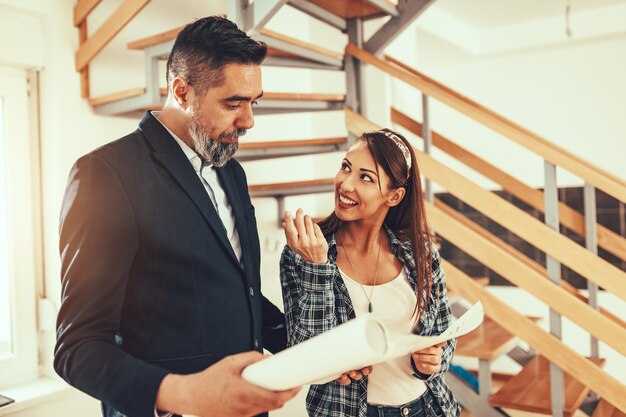 El agente inmobiliario le muestra la casa a una mujer joven y le cuenta las ventajas de la casa. El diseñador de interiores está discutiendo ideas de renovación con el propietario.