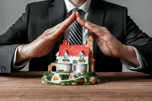 El agente inmobiliario protege una casa con sus propias manos. Negocio inmobiliario.