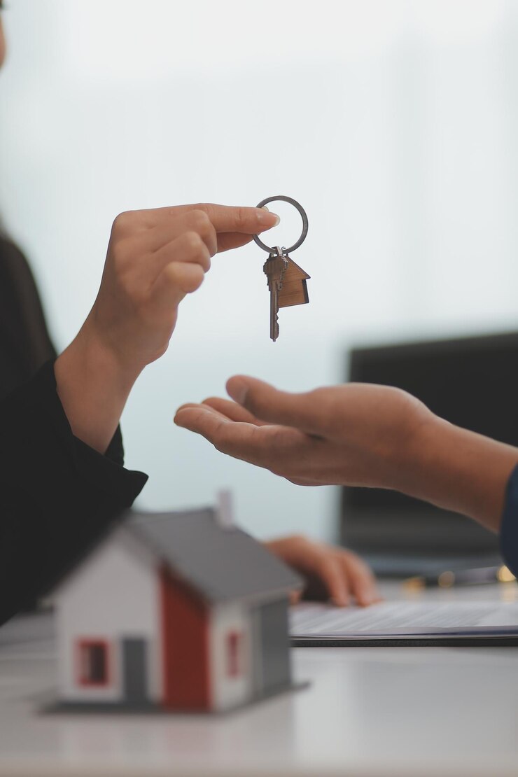 Foto agente inmobiliario que da las llaves de la casa al cliente después de firmar el contrato de contrato de bienes raíces con el formulario de solicitud de hipoteca aprobado relativo a la oferta de préstamo hipotecario y el seguro de vivienda