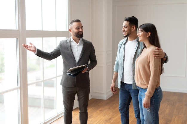 Foto agente inmobiliario en traje mostrando a los compradores nuevo apartamento