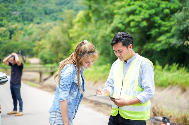 Foto el agente de seguros escribiendo los detalles en el formulario de informe de reclamación después del accidente