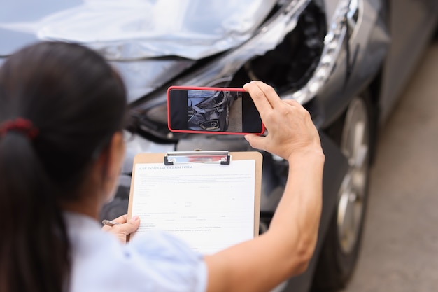 Foto el agente de seguros está filmando el daño a la evaluación de daños del automóvil accidentado después del concepto de accidente automovilístico