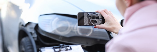 Agente de seguros tomando fotografías de coche destrozado estimación de primer plano del coste del coche dañado