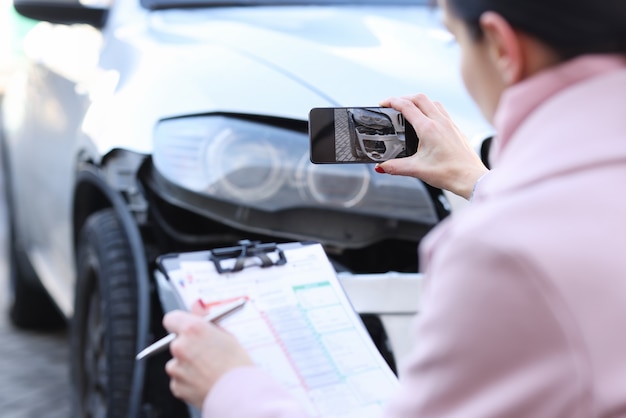 Agente de seguros tomando fotografías del primer coche destrozado. Estimación del costo del concepto de automóvil dañado