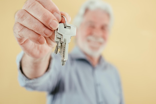 Agente senior desenfocado hombre sosteniendo llaves de casa nueva alquiler de apartamento comprar vender