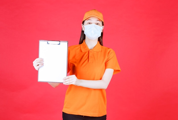 Agente de servicio femenino en código de vestimenta de color naranja y máscara que demuestra la hoja del proyecto