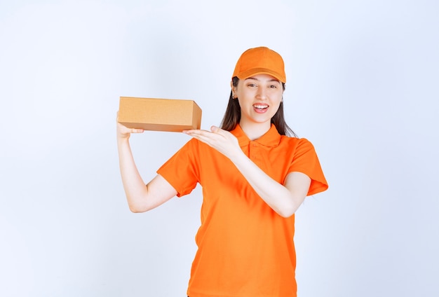 Agente de servicio femenino en código de vestimenta de color naranja sosteniendo una caja de cartón