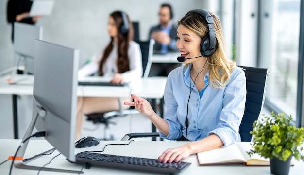 Agente de servicio de helpdesk femenina dedicada hablando con el cliente en el centro de llamadas