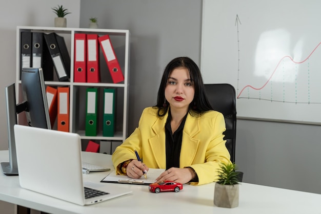 Agente de ventas femenina prepara documentos para comprar un seguro o alquilar un coche en la oficina