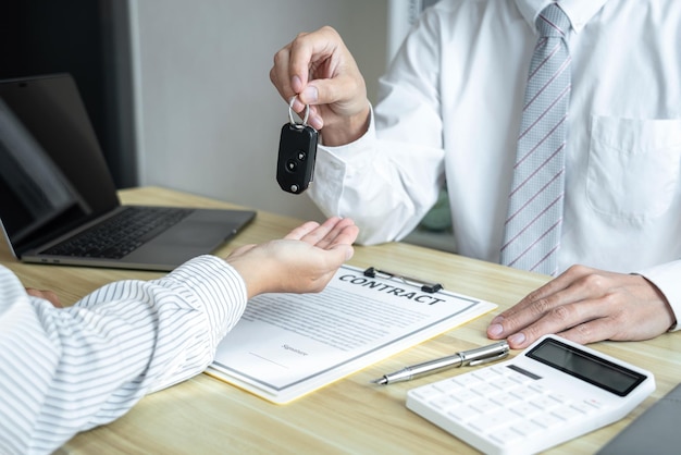 Foto agente de ventas que envía una llave al cliente después del acuerdo de buen trato contrato de seguro de préstamo de automóvil exitoso compra o venta de vehículos nuevos