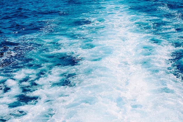 Agita, espuma y despierta en el océano con agua azul causada por un crucero.