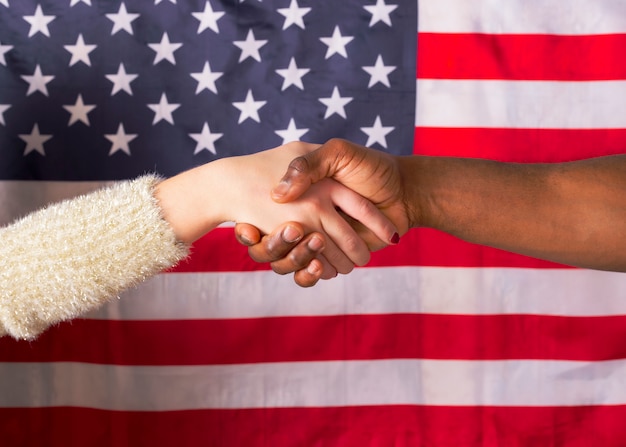 Foto agitar las manos y la mano blanca, interracial, sobre la bandera americana