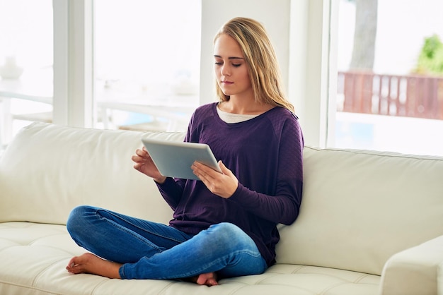 Agora ela pode blogar de qualquer lugar Foto completa de uma jovem atraente usando seu tablet enquanto relaxa em casa