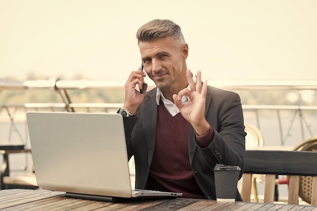 Agora isso é o que eu chamo de OK Homem bonito show OK falando no telefone Acordo e permissão Trabalho de gerente de projeto no cyber café Estilo de vida moderno Comunicação empresarial Tecnologia móvel