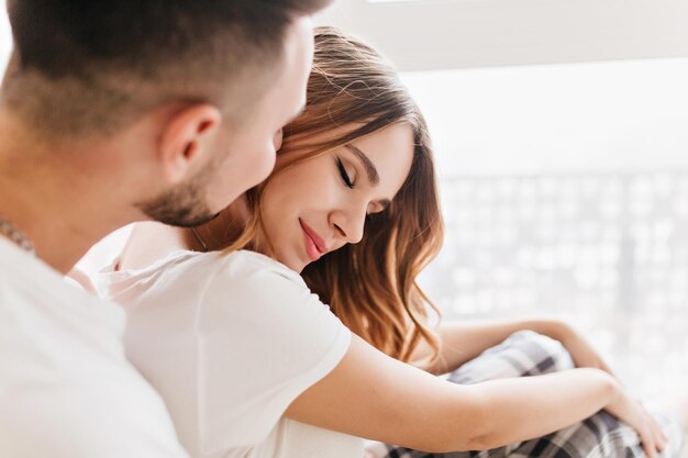 Agradable chica caucásica en camiseta blanca relajante con novio. Foto interior de escalofriante pareja europea pasando el fin de semana juntos.