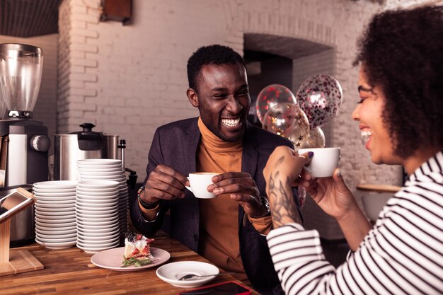 Agradable cita. Feliz pareja positiva tomando café juntos mientras está en la fecha