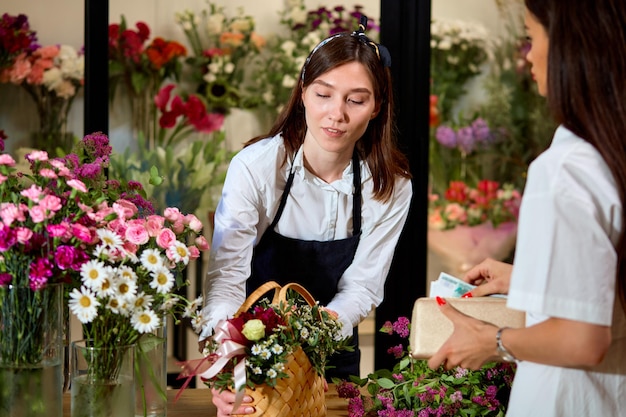 Agradable empresaria confiada propietario de invernadero de naranjos regalar flores al cliente