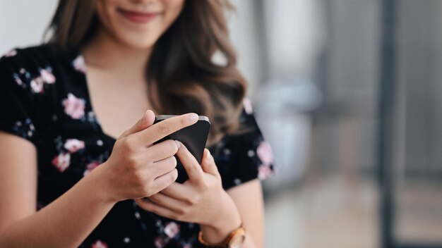 Agradable joven feliz usando un teléfono inteligente mientras está sentado en la oficina