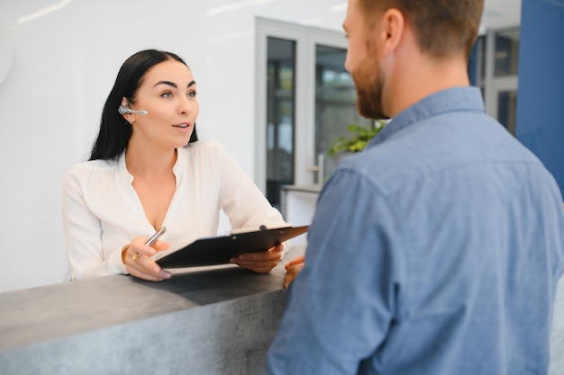 Agradable mujer amable hablando con el cliente mientras está de pie en la recepción