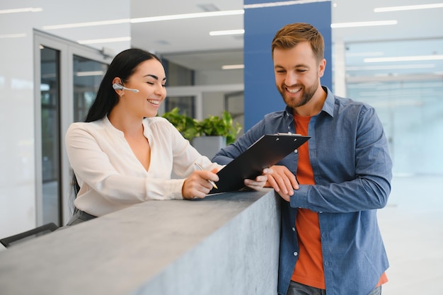 Foto agradable mujer amable hablando con el cliente mientras está de pie en la recepción