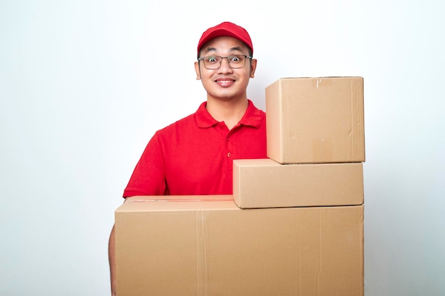 Agradável e sorridente entregador de correio asiático em uniforme vermelho, traz encomendas para a porta, carrega caixas com pedidos