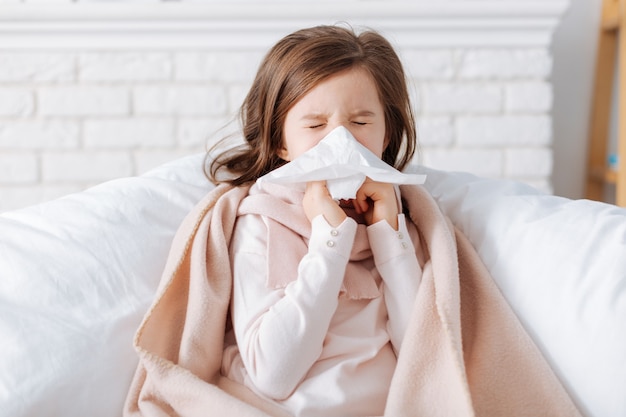 Agradável menina doente se sentindo cansada e usando lenço enquanto sofre de frio