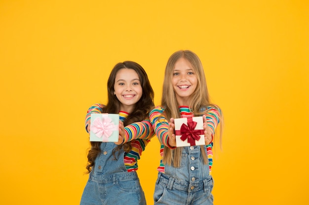 Agradecido por cada regalo del destino Amigos felices Estar agradecido por todo Enseñar a los niños a ser agradecidos Los niños sostienen cajas de regalo con fondo amarillo Los niños están encantados con los regalos Las niñas celebran las vacaciones