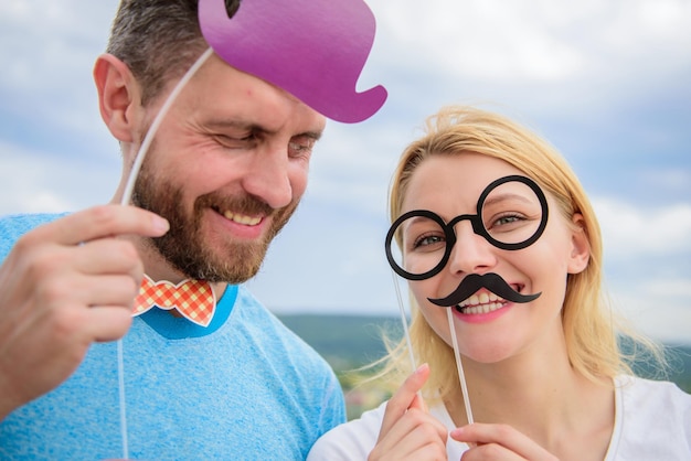 Agrega un poco de diversión Hacer fotos divertidas fiesta de cumpleaños Solo por diversión Concepto de humor y risa Pareja posando con accesorios de fiesta fondo de cielo Accesorios de fotomatón Hombre con barba y mujer divirtiéndose fiesta