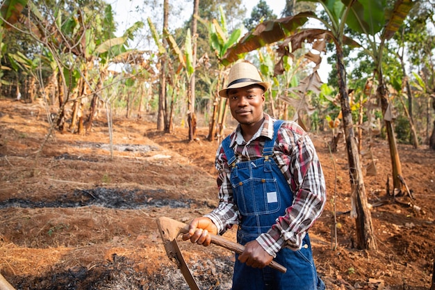 Agricultor africano trabalha no campo com o cultivador de enxada no trabalho em sua plantação