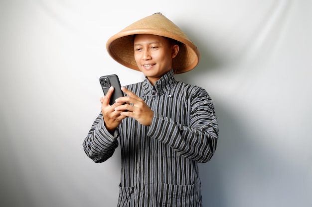 Foto agricultor asiático feliz enquanto segura um telefone celular isolado em fundo branco