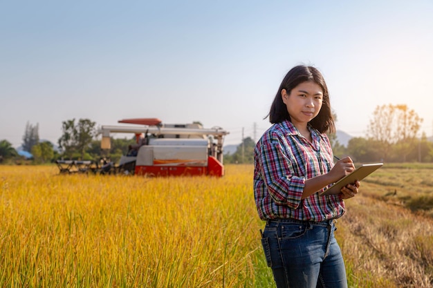 Agricultor asiático que usa la tableta para controlar y registrar la información de la cosecha