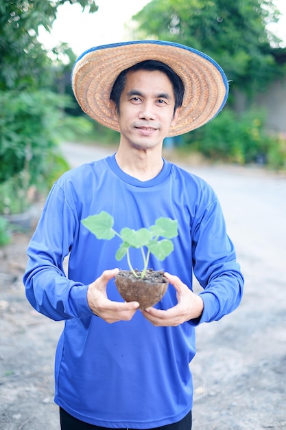 Agricultor asiático segurando uma pequena planta para agricultura
