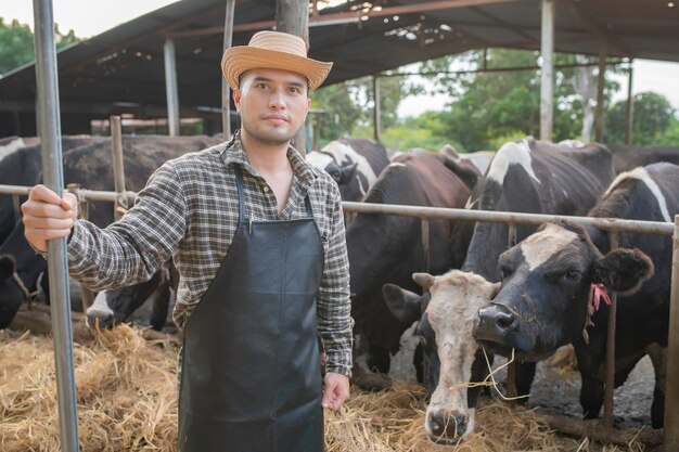 Agricultor asiático Trabajar en una granja lechera rural fuera de la ciudadJóvenes con vaca