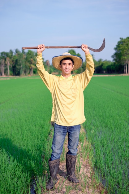 Agricultor asiático usa camisa amarela em pé e segurando a ferramenta na cabeça no green