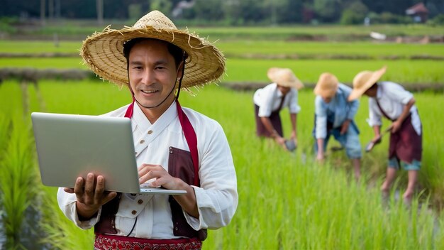 Agricultor en el campo de arroz con una computadora portátil