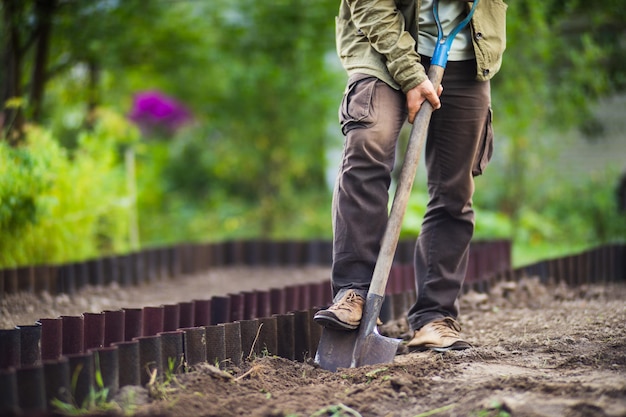 El agricultor cava el suelo en el huerto Preparando el suelo para plantar verduras Concepto de jardinería Trabajo agrícola en la plantación