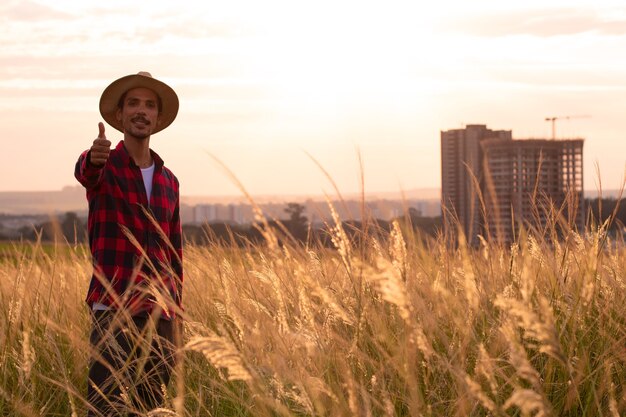 Agricultor com chapéu em plantação de fazenda no pôr do sol.