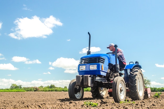 Foto un agricultor conduce un tractor en un campo agrícola vista inferior aflojar la superficie de cultivo de la tierra