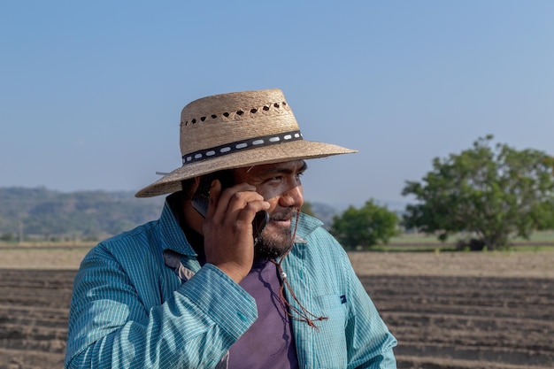 Agricultor conectado con tecnología agrícola haciendo una llamada telefónica en el campo de cultivo