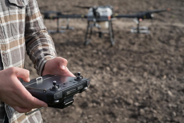 Un agricultor con un control remoto en sus manos establece los parámetros del campo para fumigar con un agrodrone las últimas tecnologías de aplicación de fertilizantes