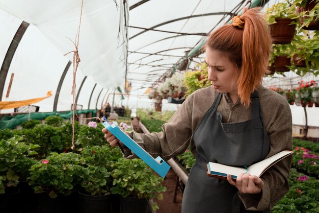 el agricultor controla las lecturas de los instrumentos de medición higrómetro y termómetro en invernadero