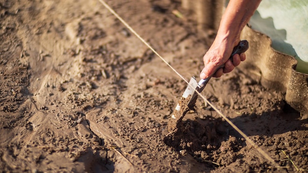 Agricultor cultivando terra no jardim com ferramentas manuais Afrouxamento do solo Conceito de jardinagem Trabalho agrícola na plantação