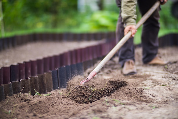 Agricultor cultivando tierra en el jardín con herramientas manuales Aflojamiento del suelo Concepto de jardinería Trabajo agrícola en la plantación