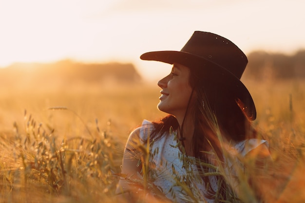 Foto agricultor de mulher em retrato de perfil de chapéu de cowboy no campo agrícola no pôr do sol.