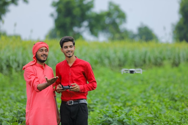 Agricultor e agrônomo indiano usando drone em campo agrícola