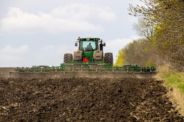 Agricultor em trator manuseia campo na primavera