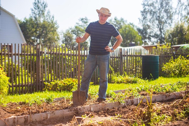 El agricultor está de pie con una pala en el jardín Preparando el suelo para plantar verduras Concepto de jardinería Trabajo agrícola en la plantación